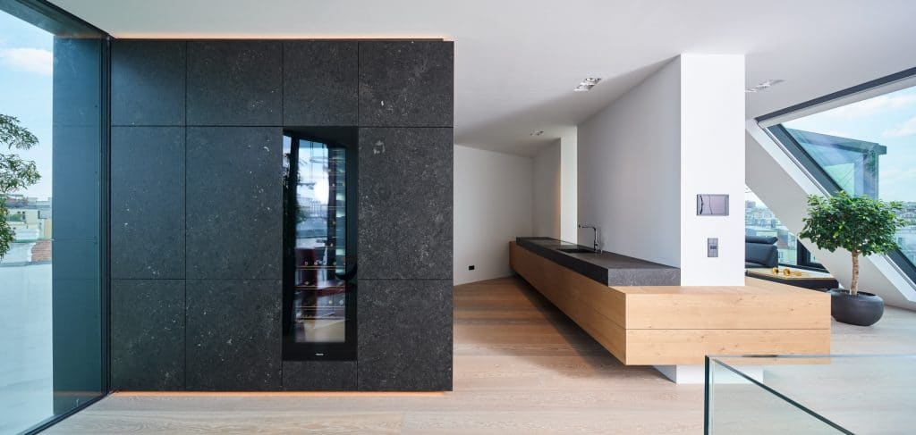 Die Wohnküche im Penthouse H. wurde in schwarzem Kalkstein (Pierre Bleu Pec) mit grober Oberfläche ausgeführt. Die rohe Haptik des handgeschliffenen Steins setzt auf Natürlichkeit auf der Fläche und an der Wand.