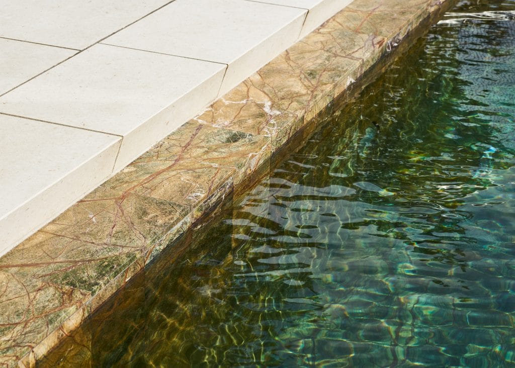 Architekturvilla mit stilvollem Natursteinpool aus Rain Forest Green Marmor sowie einer Wandverkleidung der Fassade aus White Shell Kalkstein