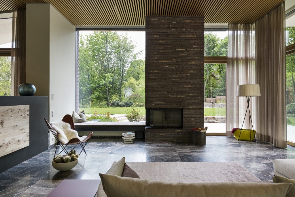 Die Villa am Waldrand von Atelier Claus Radler setzt auf zeitlose und dauerhafte Materialien. Neben dem Pool, den Steinmauern, den Terrassen und der Wegeführung in der sehr natürlich gewachsenen Gartengestaltung von Clemens Lutz kommt im Wohnzimmer ein schöner türkischer Marmor von Breitwieser zum Einsatz